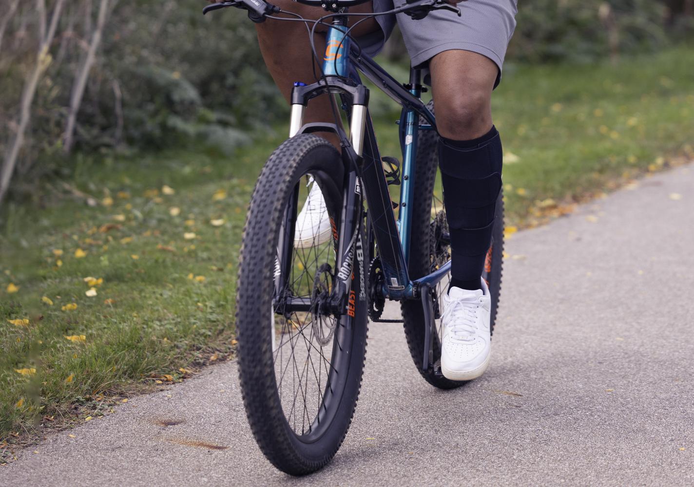 Man riding a bike while wearing a leg wrap